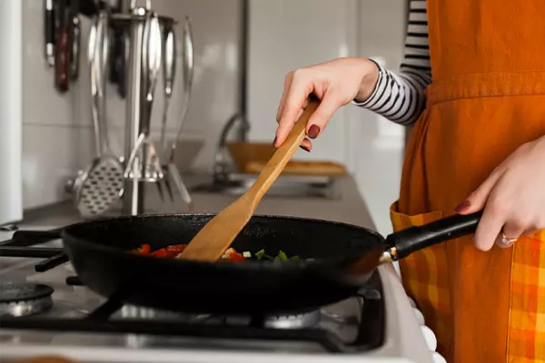 Imagem de uma mulher fritando carne na frigideira