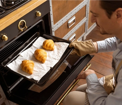 Homem colocandocroissant no formo par assar.